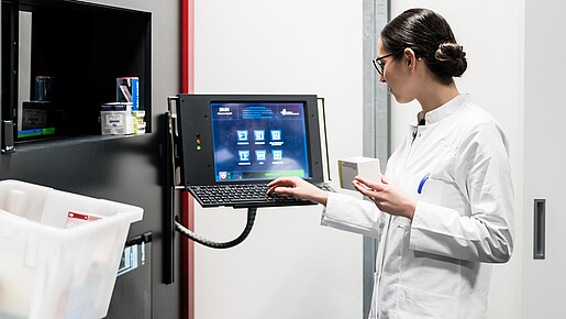 Low-angle rear view of an experienced female pharmacist using a computer while managing the drug stock in a contemporary pharmacy with modern technology