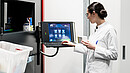 Low-angle rear view of an experienced female pharmacist using a computer while managing the drug stock in a contemporary pharmacy with modern technology
