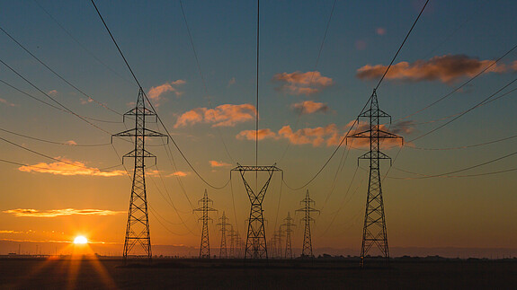Die Strombank - Ideen zur Reform des Energiemarkts Stromleitungen und Strommasten in der Morgendämmerung