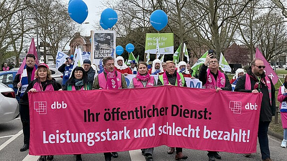 1.000 Beschäftigte demonstrieren in Wiesbaden Das Foto zeigt Demonstrierende in Wiesbaden am 25. März. 2026. Sie tragen Streikwesten und halten Transparente.