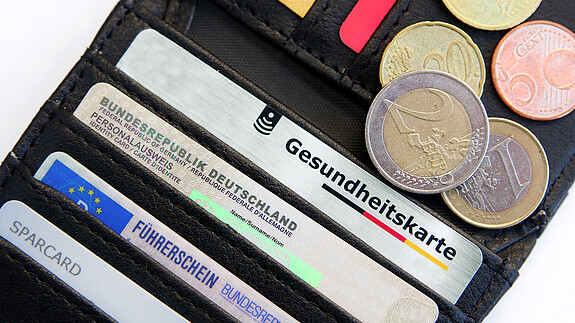 260420_Geyer zur GKV-Reform_Colourbox Das Bild zeigt eine Geldbörse mit einer Gesundheitskarte, Ausweisdokumenten und Münzen.