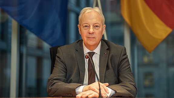Markus Töns, MdB Markus Töns sitzt vor der deutschen und europäischen Flagge