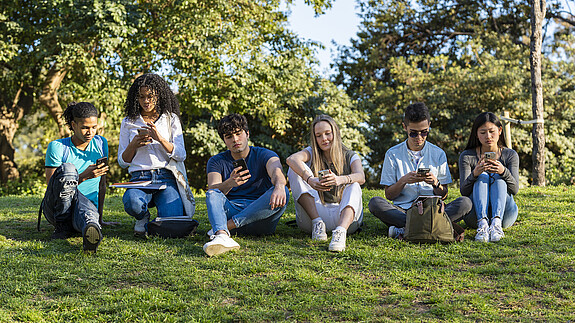 Trendstudie Jugend in Deutschland - dbb jugend sieht neue Regierung in der Bringschuld Group of teenage friends looking at phone in the park on green grass. Three boys and three girls
