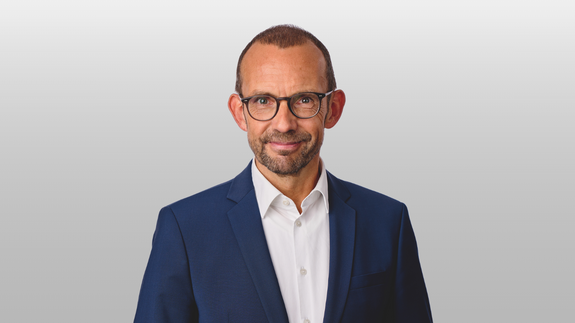 Foto von einem weißen Mann mit Anzug und Brille, der in die Kamera blickt. Es handelt sich um Thomas Röwekamp, Vorsitzender des Verteidigungsausschusses des Deutschen Bundestages