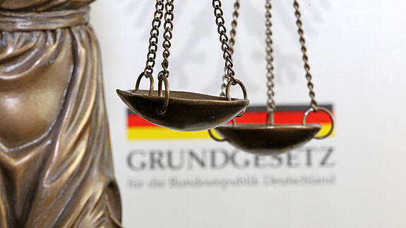 Tag des Grundgesetzes Nahaufnahme einer Justitia vor dem deutschen Grundgesetzbuch