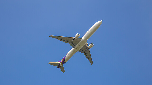Zu sehen ist ein Flugzeug am Himmel