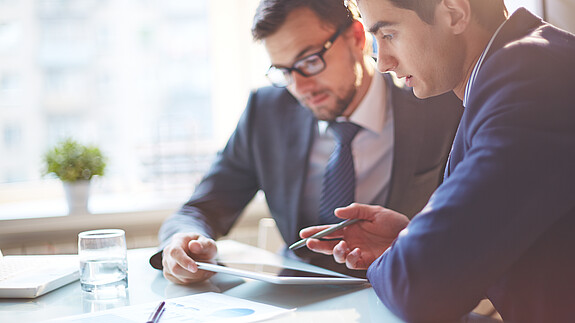 Digitalisierung Zwei Männer im Büro sehen gemeinsam auf Tablet und besprechen sich