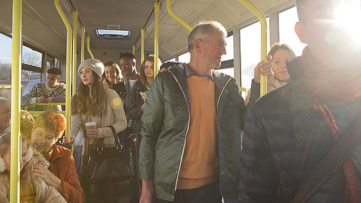 Mobilität und Teilhabe Blick in den Innenraum eines Busses auf stehende und sitzende Passagiere aus allen Altersgruppen